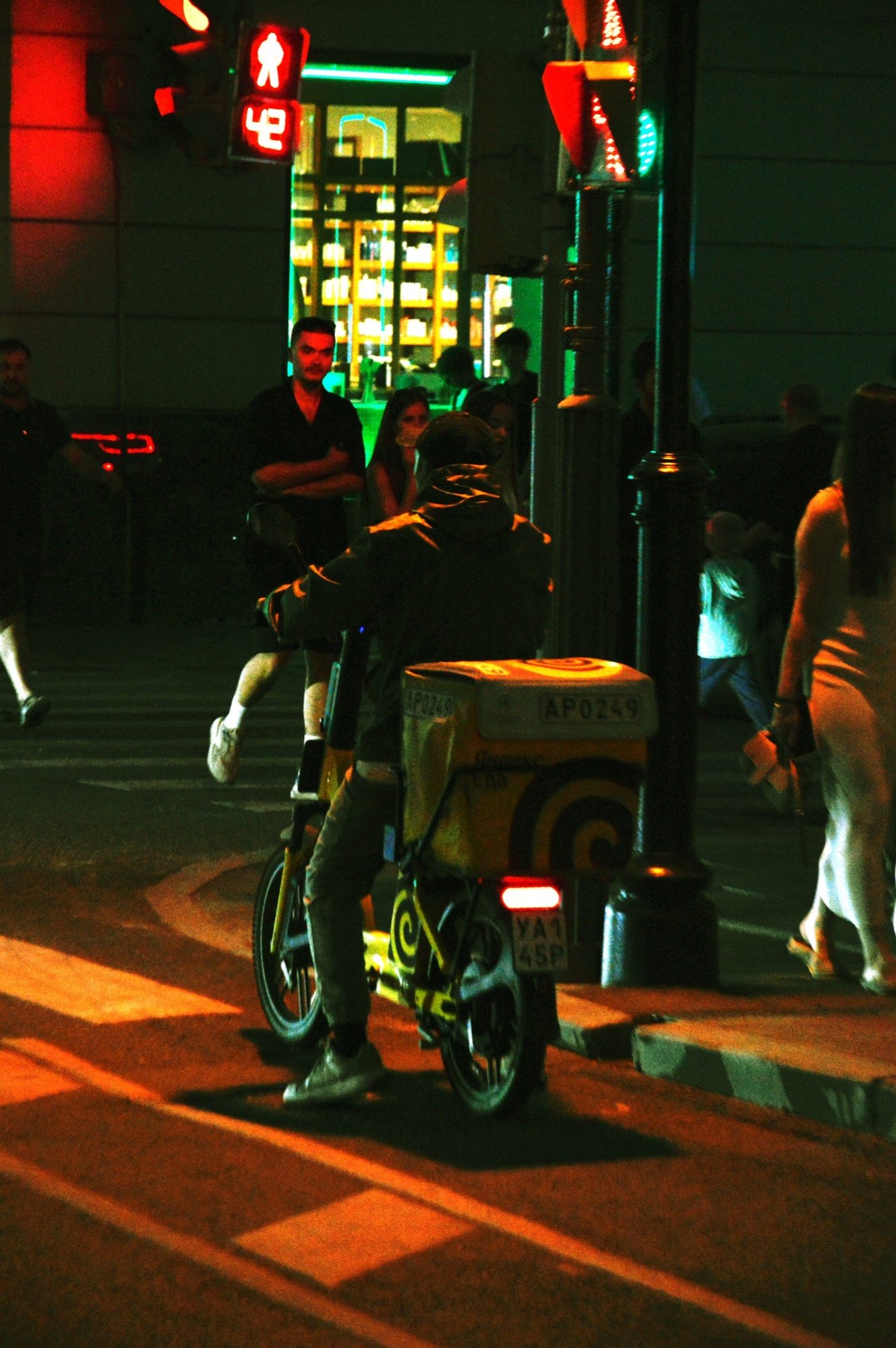 A delivery rider on a scooter in the city at night